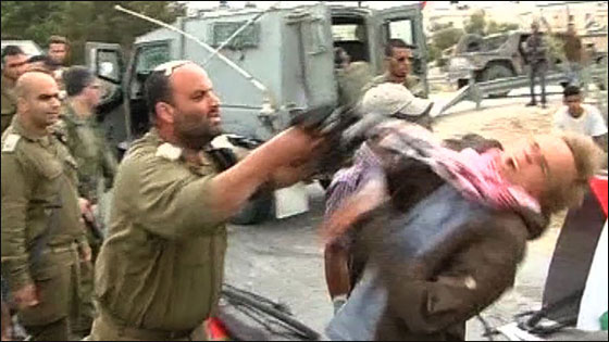 بالصور ..ضابط اسرائيلي يضرب ناشط سلام اجنبي ببندقيته!!