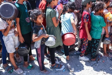 أطفال يتجمعون عند نقطة توزيع مواد غذائية في مخيم جباليا شمالي قطاع غزة