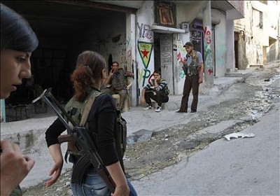 Des femmes kurdes armées passant devant des miliciens le 19-6-13 à Cheikh Maksoud à Alep