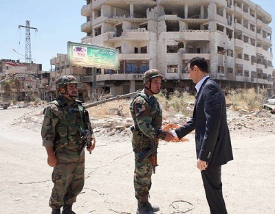 Le président Assad saluant un militaire dans la localité de Darayya de la province de Damas sécurisée depuis un mois.